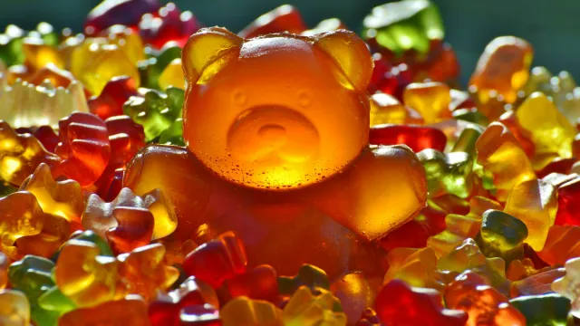 Large gummy bear among smaller colorful gummy bears.