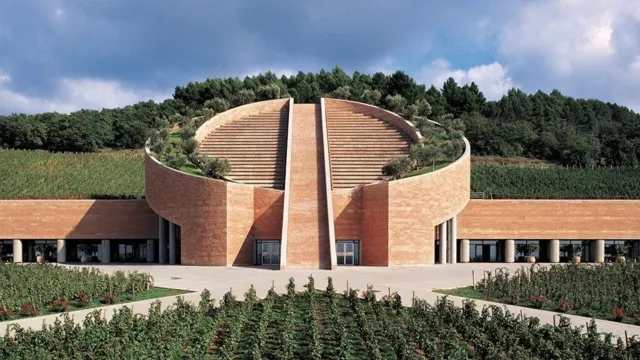 Modern brick building with vineyard and cloudy sky.