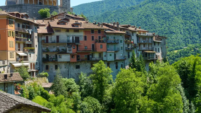 Hilltop village with colorful houses and a church tower, surrounded by lush green hills.