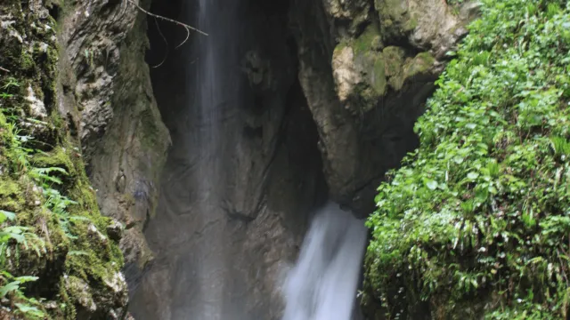 Waterfall cascading between lush green cliffs.