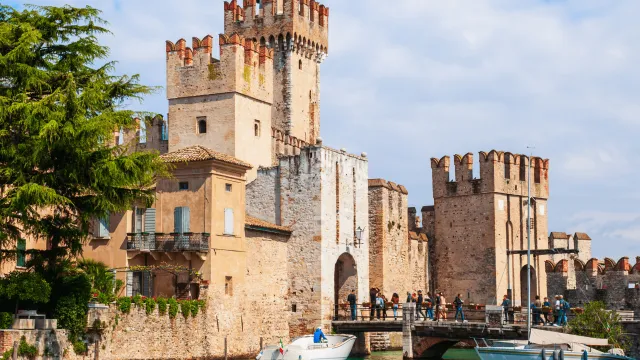 Medieval castle by a blue lake under a bright sky.