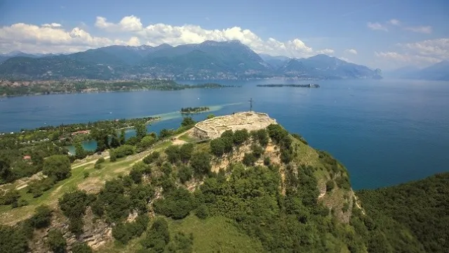 Hilltop overlooking a vast lake with distant mountains under a clear sky.