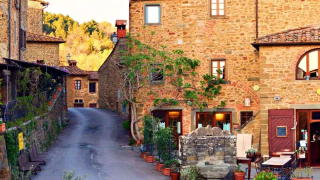 Stone buildings and a narrow street with potted plants at sunset.