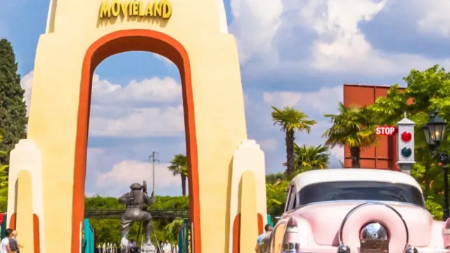 Entrance arch with "Movieland" sign and a parked vintage pink car.