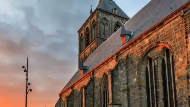 Stone church under a vibrant sunset sky with clouds.