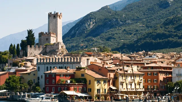 Colorful lakeside town with a castle and mountains in the background.