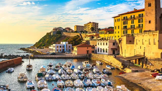 Coastal town harbor with colorful boats, vibrant buildings, and a clear blue sky.