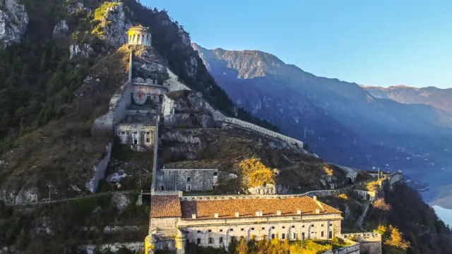 Aerial view of a mountain fortress, bathed in golden sunlight.