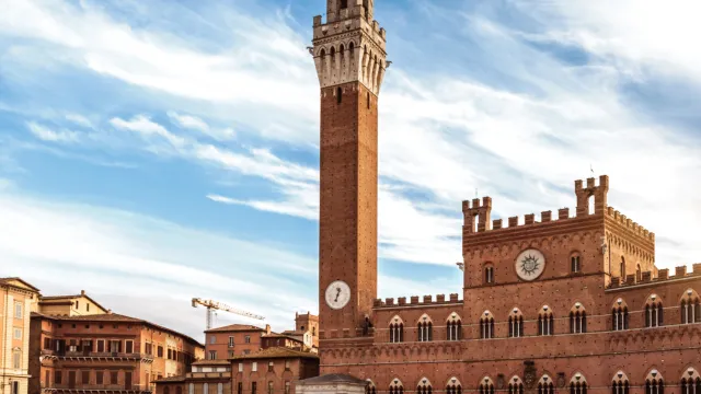 Siena's Piazza del Campo with Torre del Mangia under a blue sky.