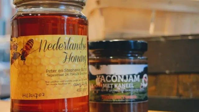 Jar of Dutch honey and a jar of bacon jam on a wooden table.