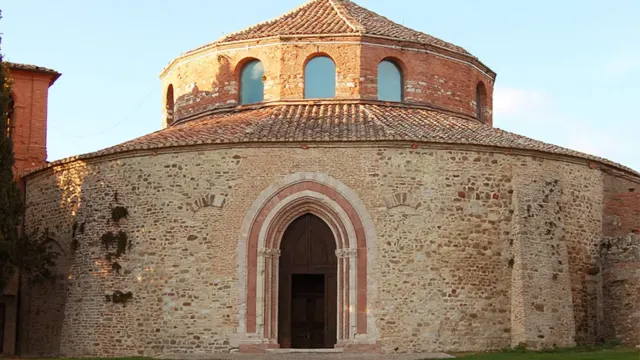 Historic round church with a brick dome, arched entrance, and grassy path.
