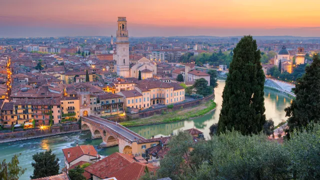 Sunset over a cityscape with a river and historic buildings.
