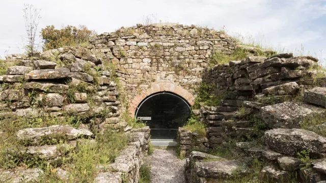 Ancient stone tunnel entrance under a cloudy sky.