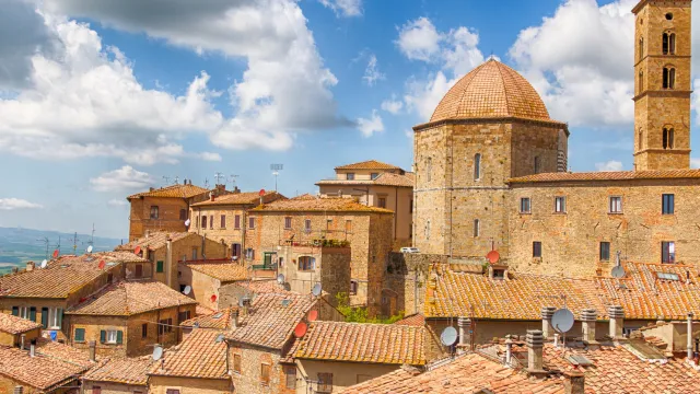 Rustic Italian town with terracotta rooftops under a partly cloudy sky.