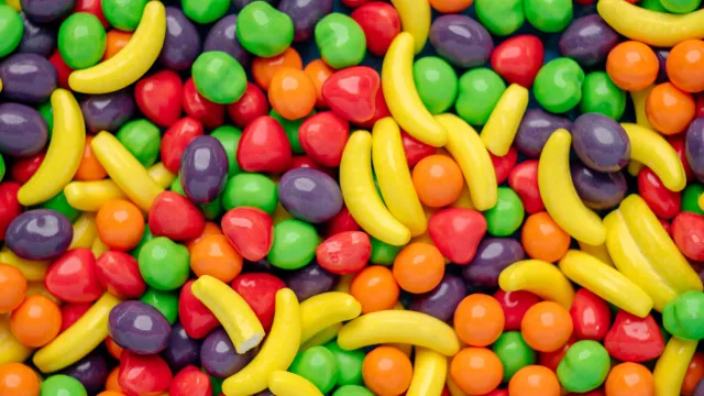 Colorful candy assortment, bananas, and round shapes fill the frame.