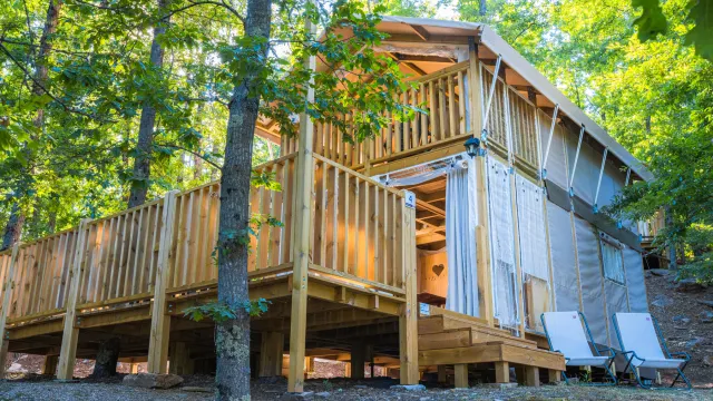Wooden cabin with a deck in a forest setting.
