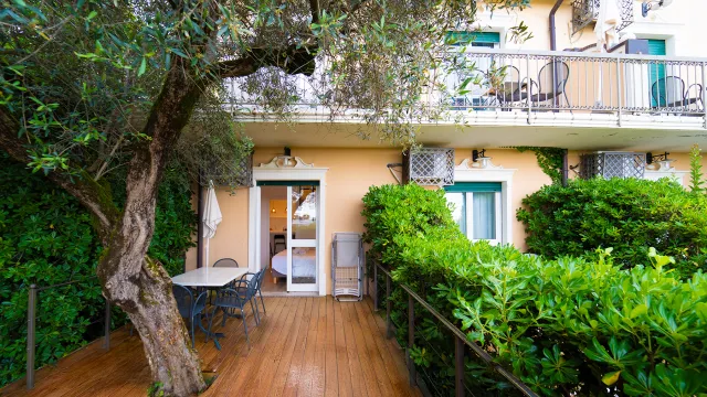 Deck with wooden flooring, lush greenery, and outdoor dining set, near a terrace.