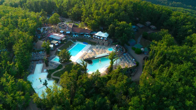 Outdoor water park surrounded by dense forest, aerial view.