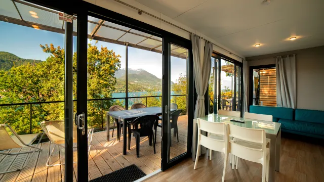 Modern dining area with glass doors overlooking a scenic mountain and lake view.