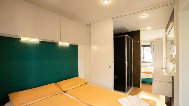 Cozy bedroom with twin beds, teal headboard, and bathroom in the background.