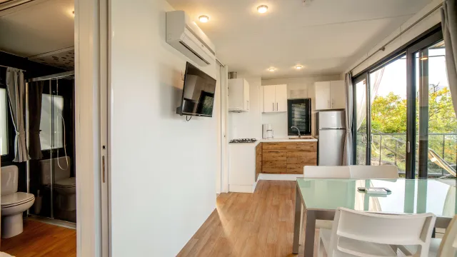 Modern kitchen and dining area with large windows and a view of greenery.