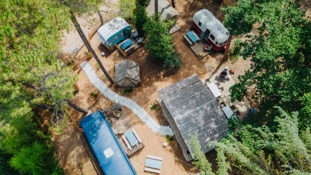Aerial view of a campsite with trailers and picnic tables among trees.