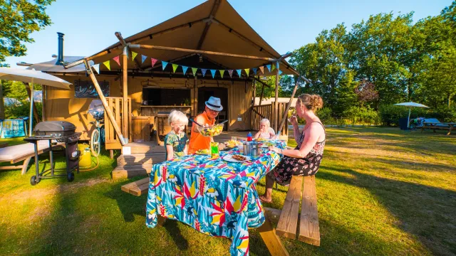 Family dining outdoors at a campsite with festive decor.