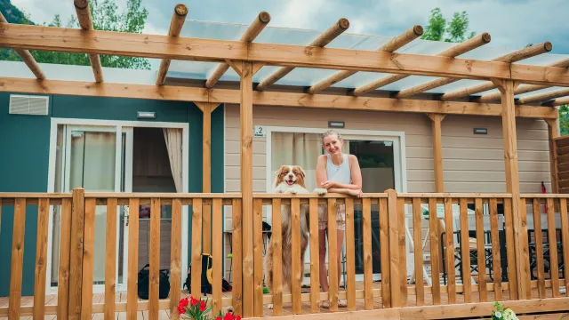 Woman and dog on a wooden porch with flowers in the foreground.