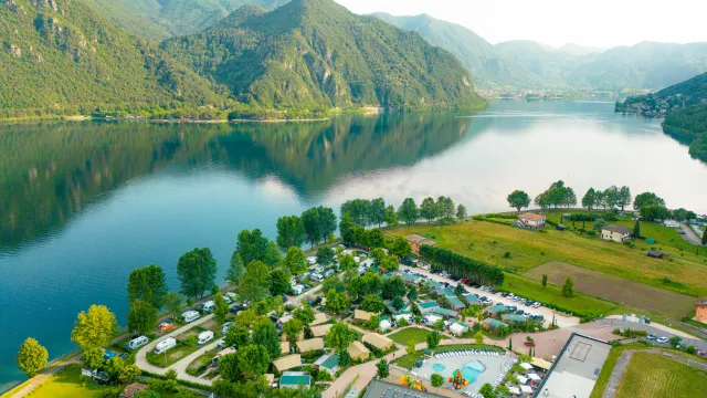 Aerial view of a lakeside campsite with mountains in the background.