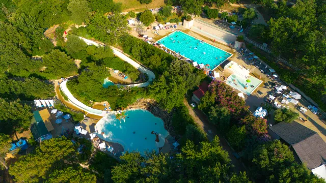 Aerial view of a water park with pools and slides surrounded by trees.