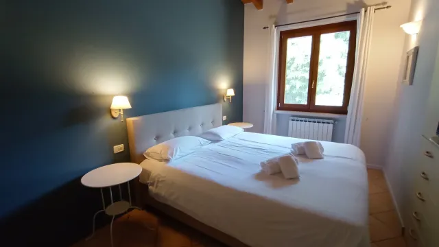 Cozy bedroom with blue accent wall, double bed, and wooden ceiling beams.