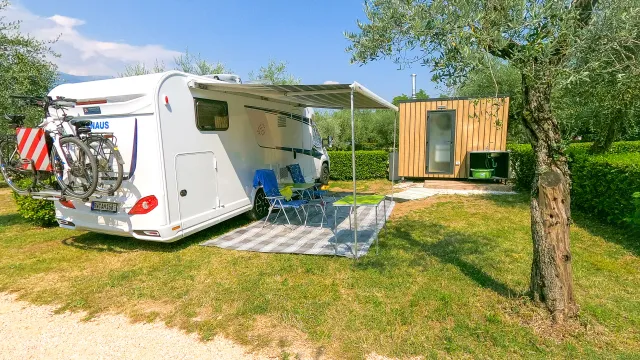 Camper van parked on grass beside a small wooden cabin.