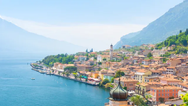 Sunny coastal town with colorful buildings, mountains, and blue water.