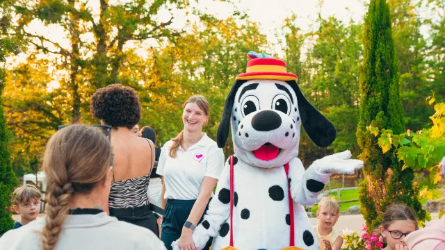 spotty with colorful hat greeting people outdoors.