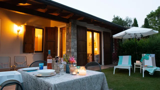 Cozy patio at twilight with a candlelit dining table, lounge chairs, and umbrella.