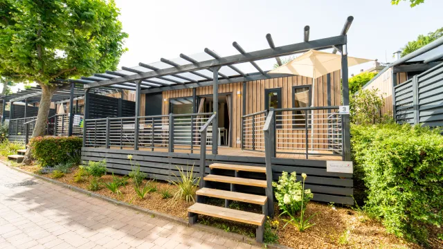 Modern Cottage Next L Evo with wooden deck surrounded by greenery.