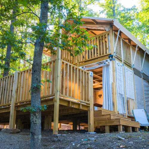 Wooden cabin with a deck in a forest setting.