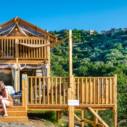 Air lodge with people seated, set against a green hillside under a blue sky.