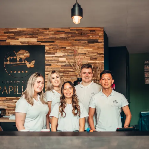 Five smiling people in uniforms behind a reception desk.