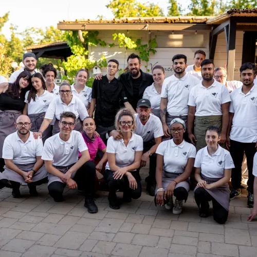 Restaurant staff group photo outside, wearing uniforms and smiling.