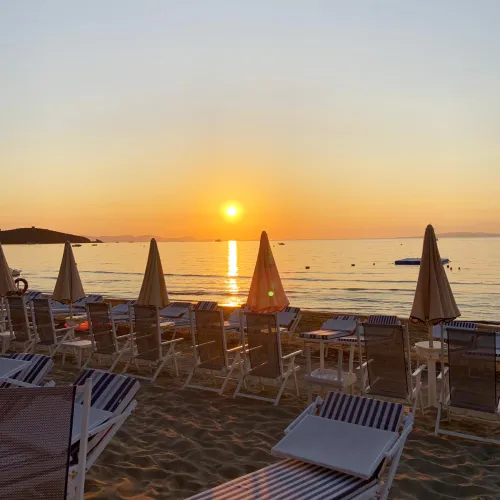 Sunset over a beach with loungers and umbrellas.
