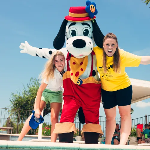 spotty with two women by a pool, under a sunny sky.