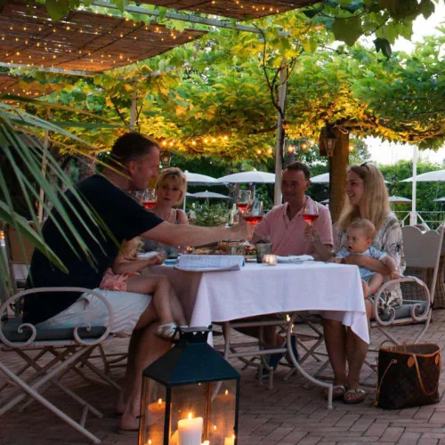 Family dining outdoors, under string lights, enjoying drinks and conversation.