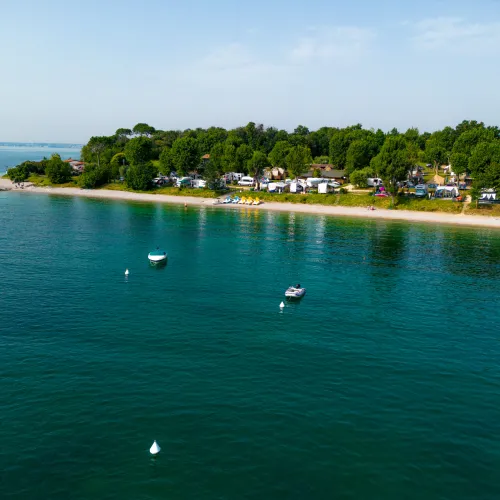 Coastal campsite with calm waters and several anchored boats.