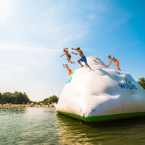 Teens jumping off inflatable iceberg into a lake.