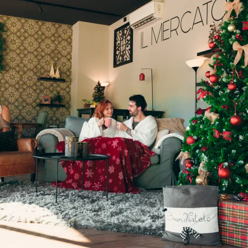 Lago Idro Winter Glamping christmas.jpg Cozy couple by Christmas tree in warm, festive living room.