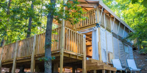 Wooden cabin with a deck in a forest setting.