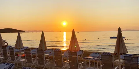 Sunset over a beach with loungers and umbrellas.