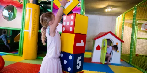 Child stacking colorful numbered blocks in play area.