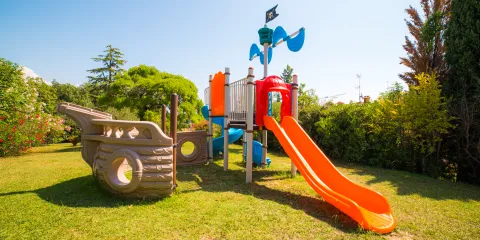 Playground with orange slide and pirate ship structure on grass.